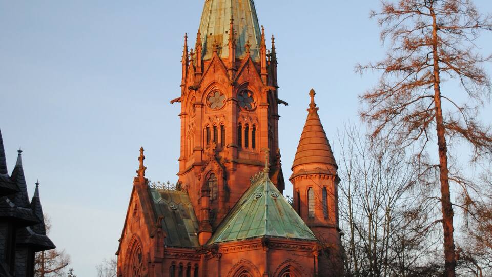 A historic church with a tall spire and a green roof.