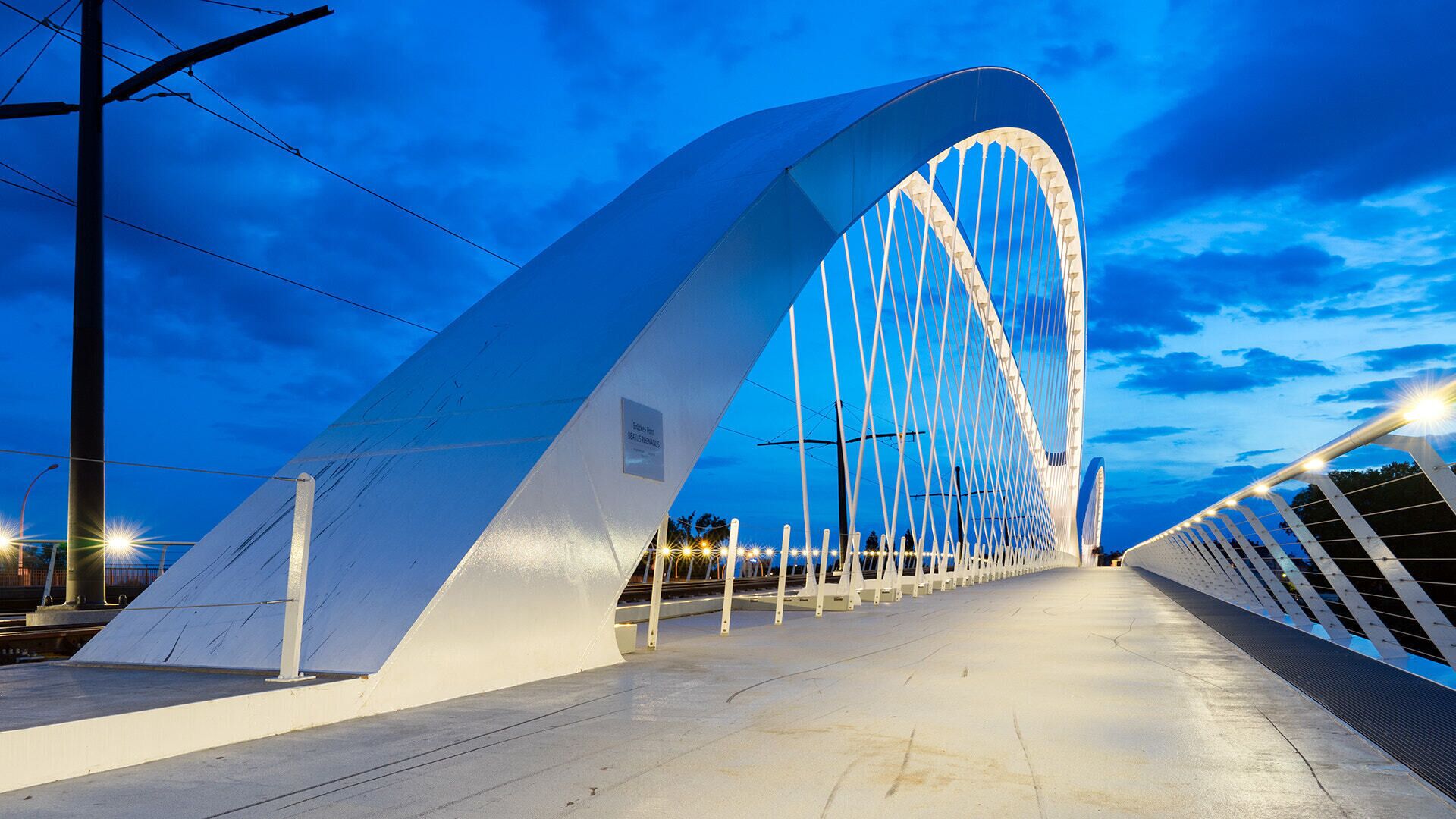 500px provided description: The new "Trambr?cke" between Kehl and Strasbourg. [#sky ,#city ,#travel ,#blue ,#night ,#train ,#tram ,#urban ,#architecture ,#bridge ,#building ,#white ,#grey ,#modern ,#outdoors ,#construction ,#perspective ,#futuristic ,#nightscape ,#no person ,#transportation system]