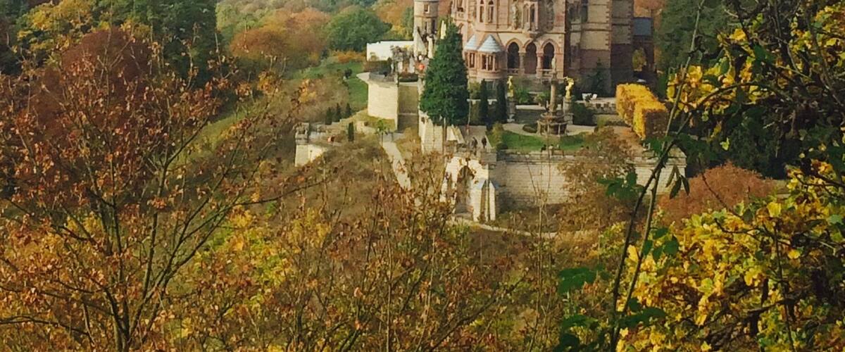 Schloss Drachenberg and view of Bonn beyond. Schloss Drachenburg is a private villa in palace style constructed in the late 19th century. It was completed in only two years (1882–84) on the Drachenfels hill in Königswinter, a German town on the Rhine near the city of Bonn. Baron Stephan von Sarter (1833–1902), a broker and banker, planned to live there, but never did.
Today the Palace is in the possession of the State Foundation of North Rhine-Westphalia. It is served by an intermediate station on the Drachenfels Railway. You can ride the train or hike from the bottom.