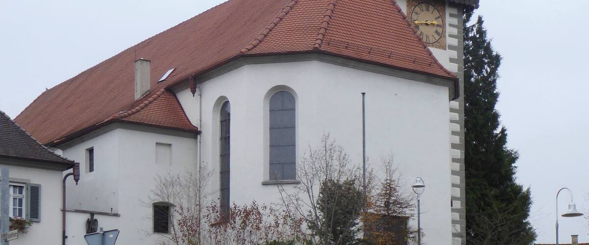 A church with a red-tiled roof and a tall bell tower.