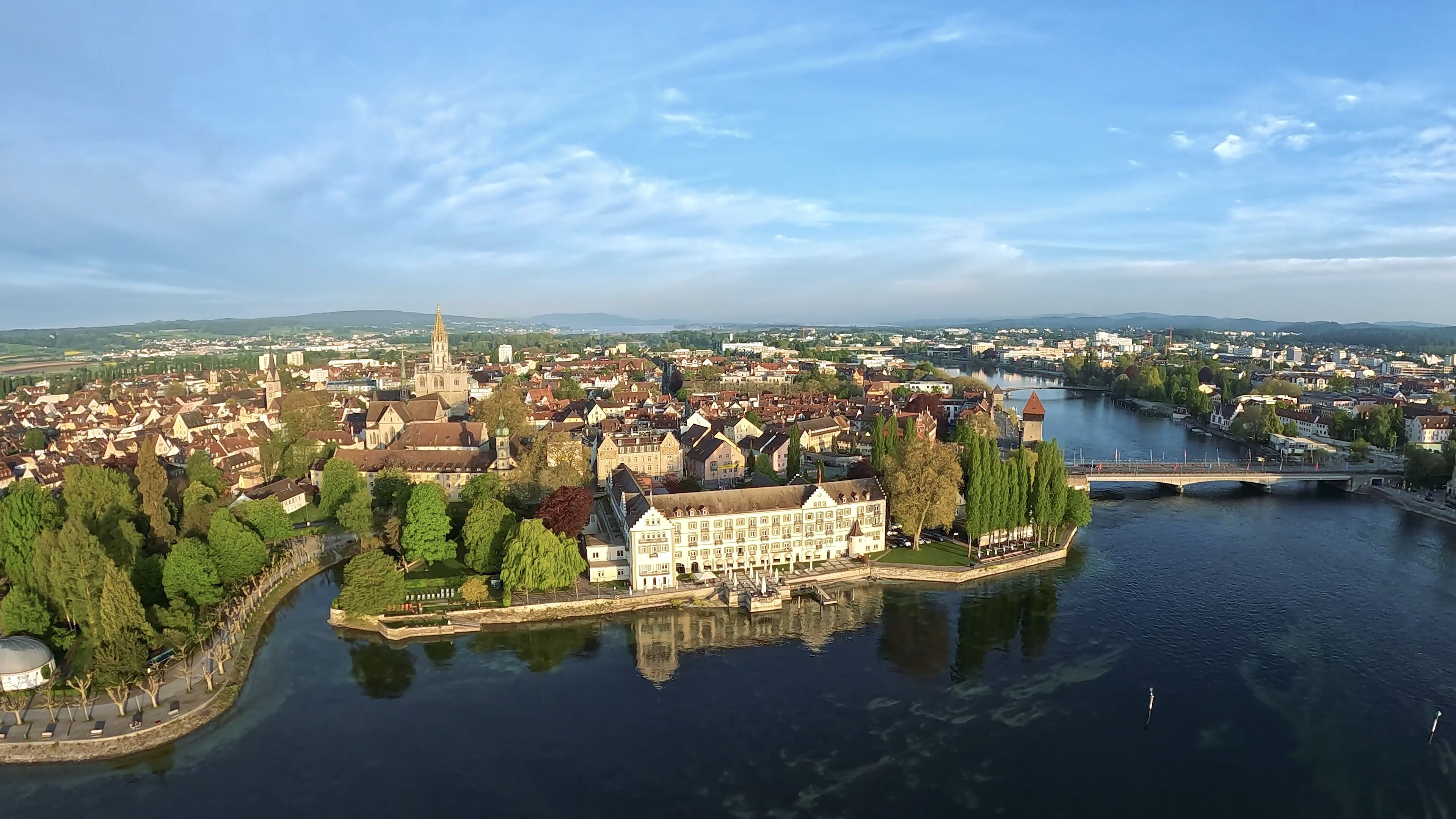 A river city with a prominent church spire, a castle-like building, and a bridge.