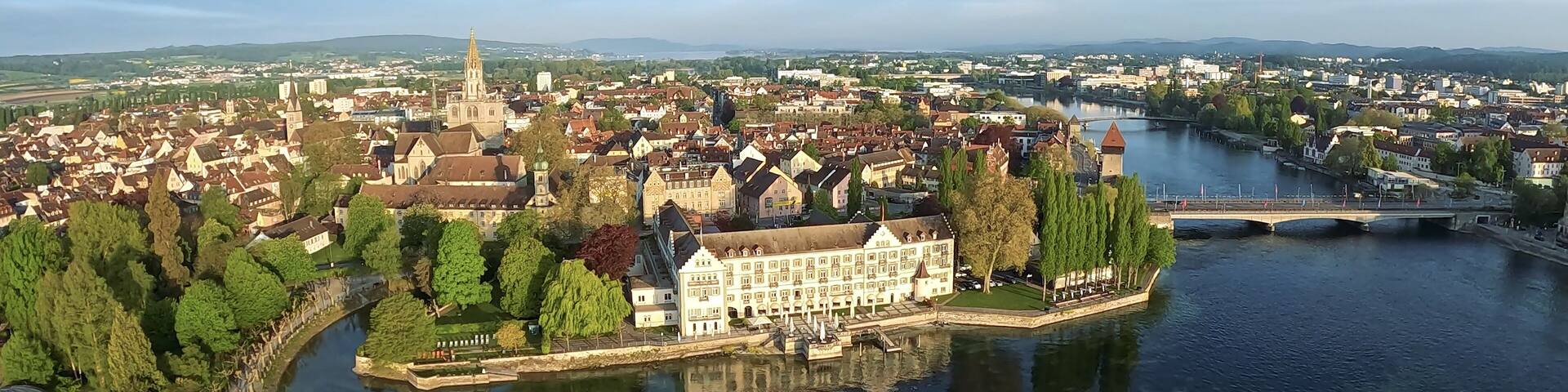 A river city with a prominent church spire, a castle-like building, and a bridge.
