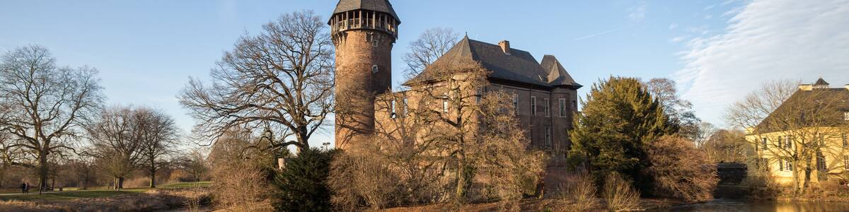 Eine historische Burg mit einem hohen Turm und einem Fluss im Vordergrund.