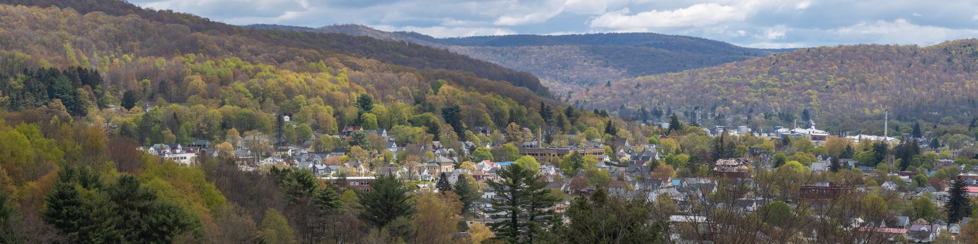 Un pueblo ubicado en un valle, con árboles de colores otoñales y colinas al fondo.