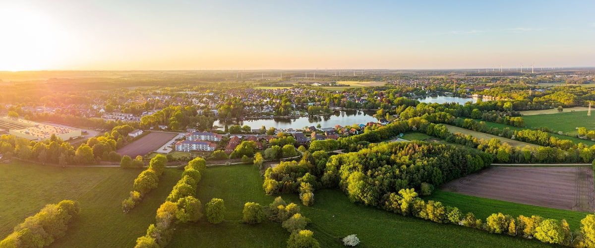 Un paysage rural avec un lac, des éoliennes et une zone résidentielle.