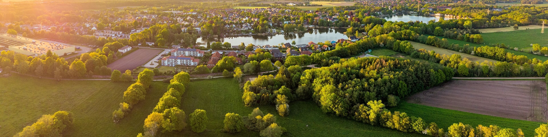 A rural landscape with a lake, wind turbines, and a residential area.