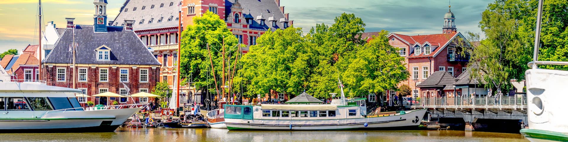 A historic town with a prominent tower, a river with boats, and traditional buildings.
