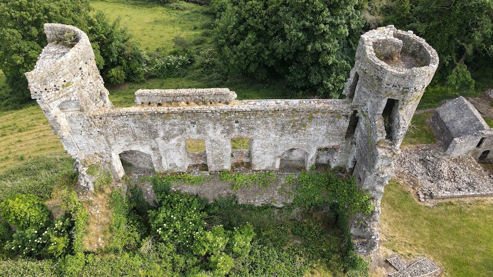A historic stone castle ruin surrounded by lush greenery.