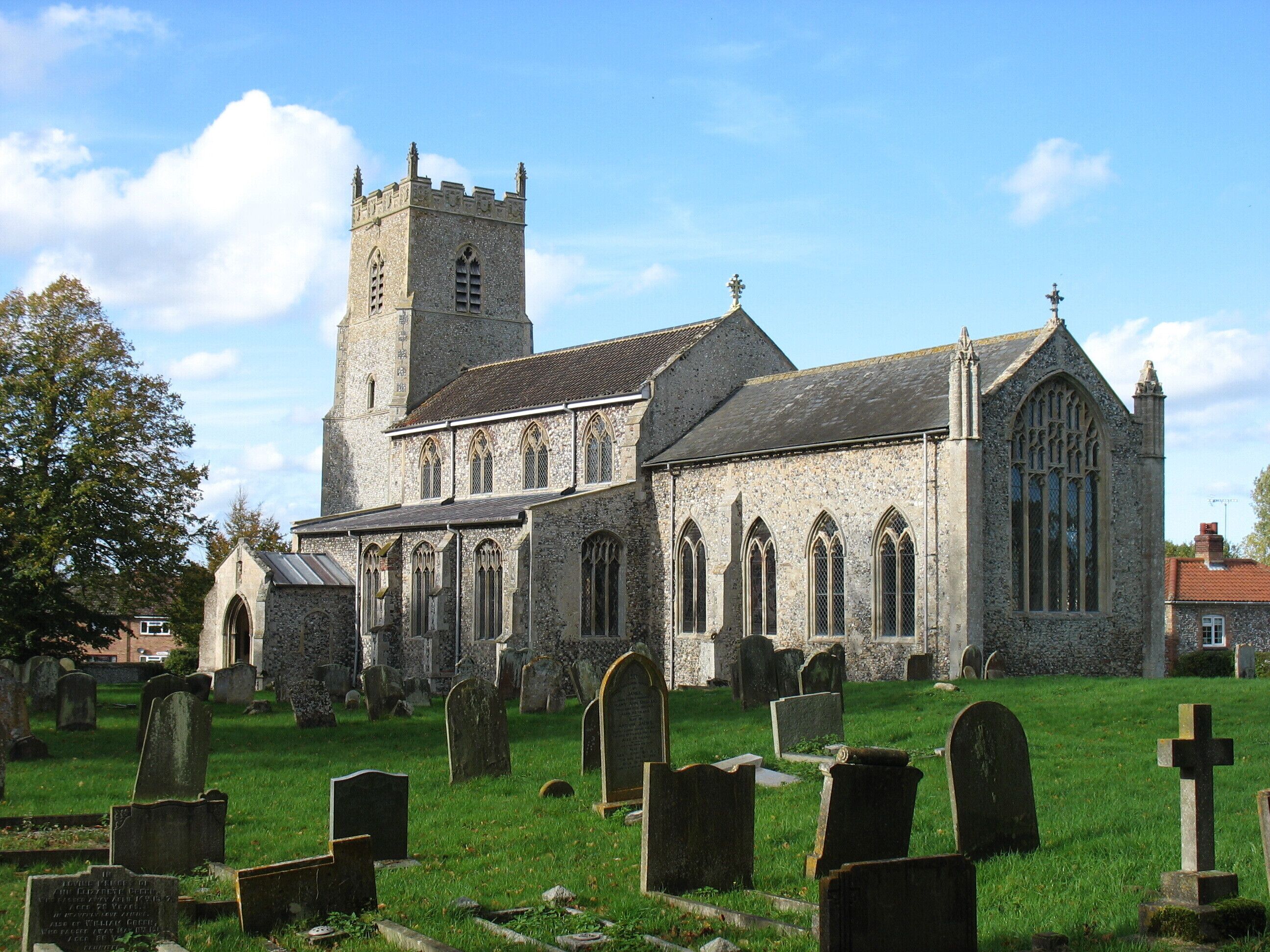 A historic church with a tall tower and a cemetery in front.