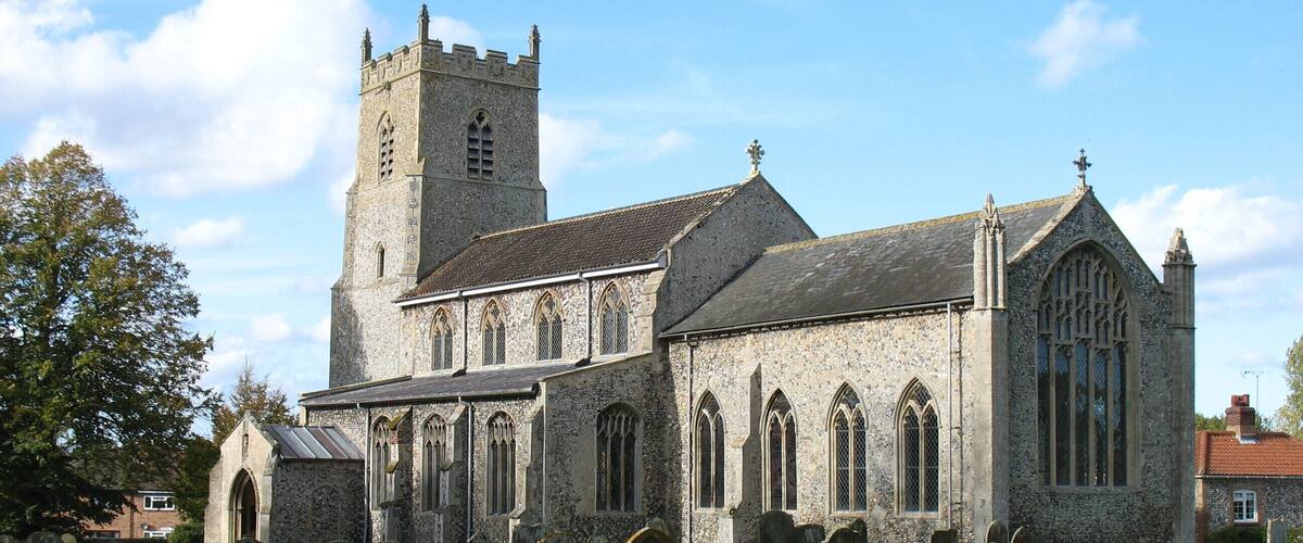 A historic church with a tall tower and a cemetery in front.