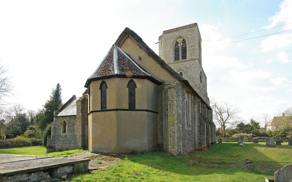 A church with a bell tower and a stone wall.