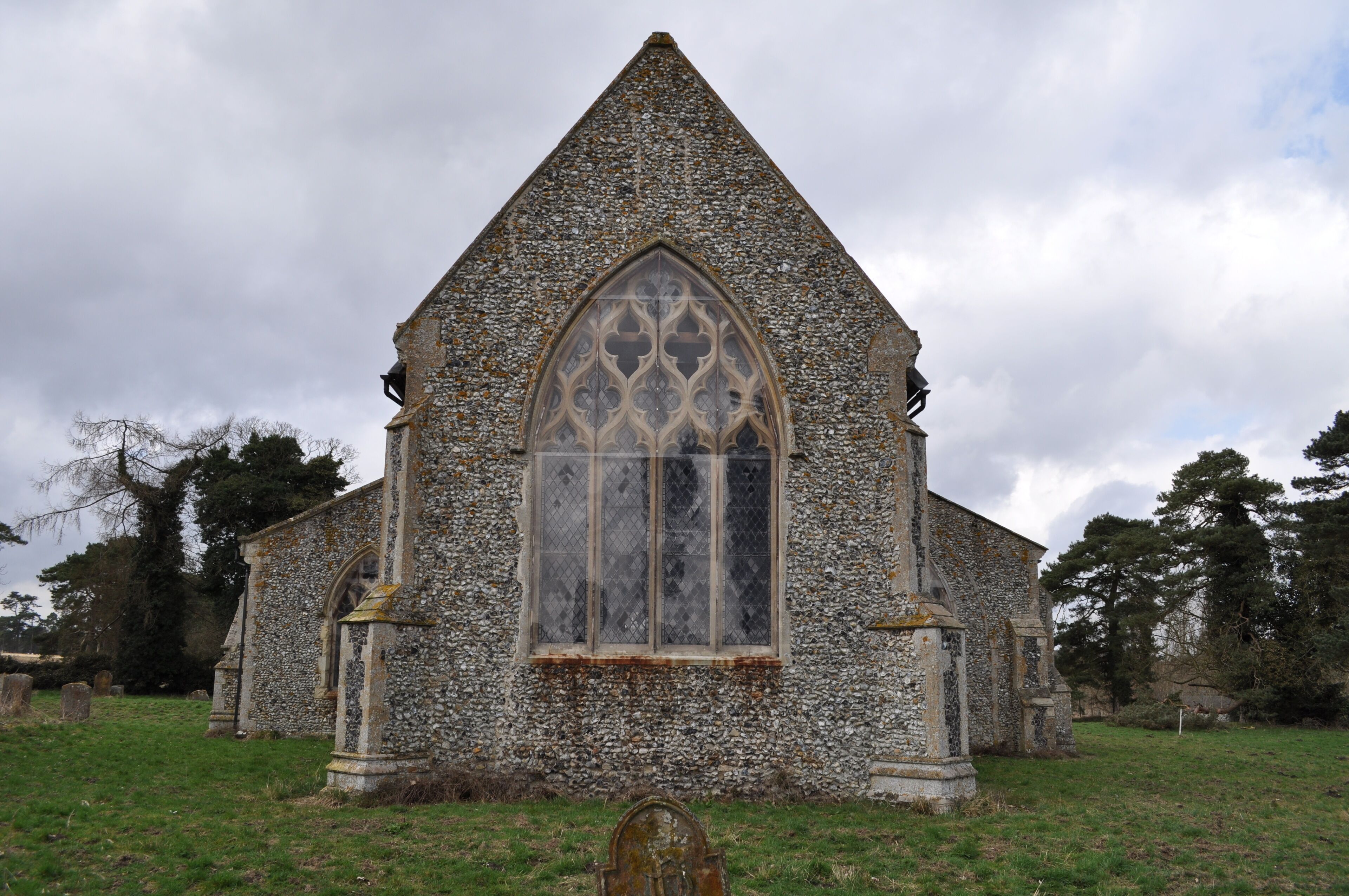 A stone church with a pointed roof and a large arched window.