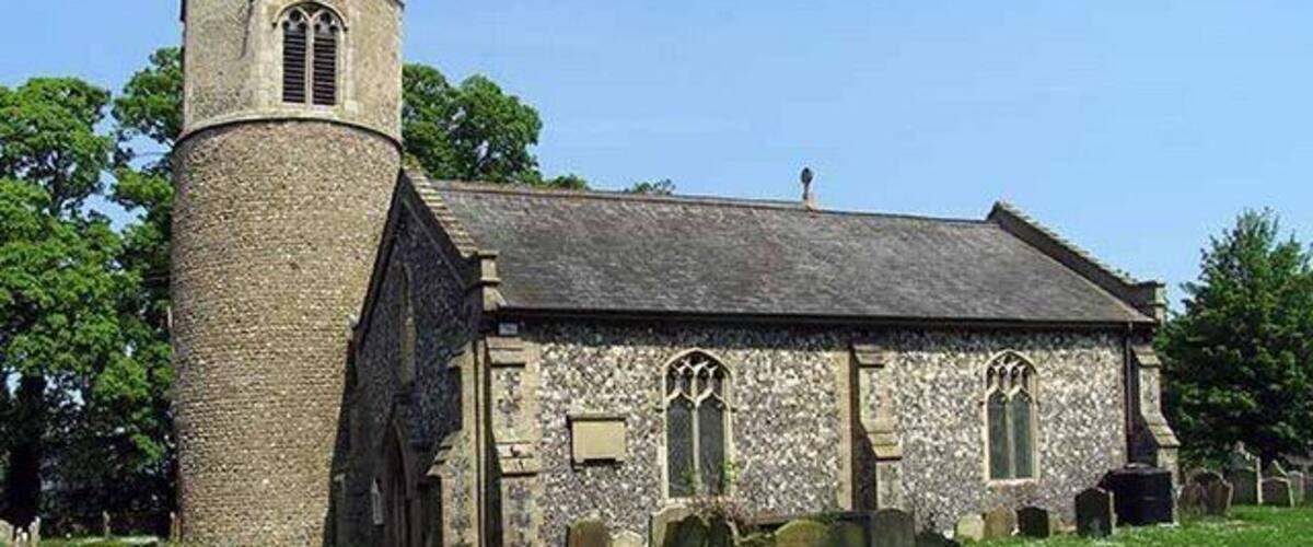 A small stone church with a bell tower and a graveyard.