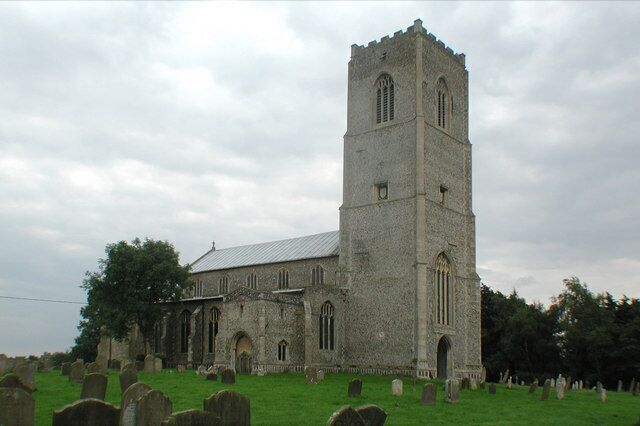 A church with a tall tower and a graveyard in front.