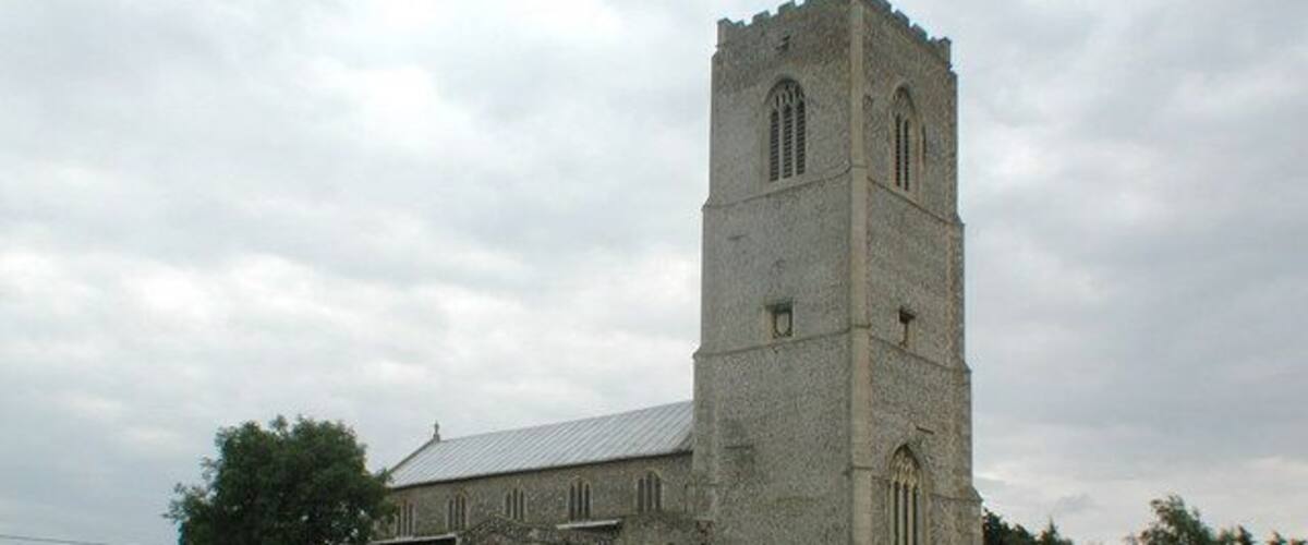 A church with a tall tower and a graveyard in front.