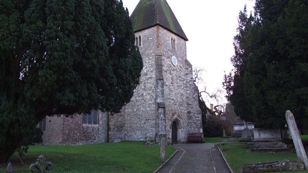 A stone church with a green roof and a clock on its tower.