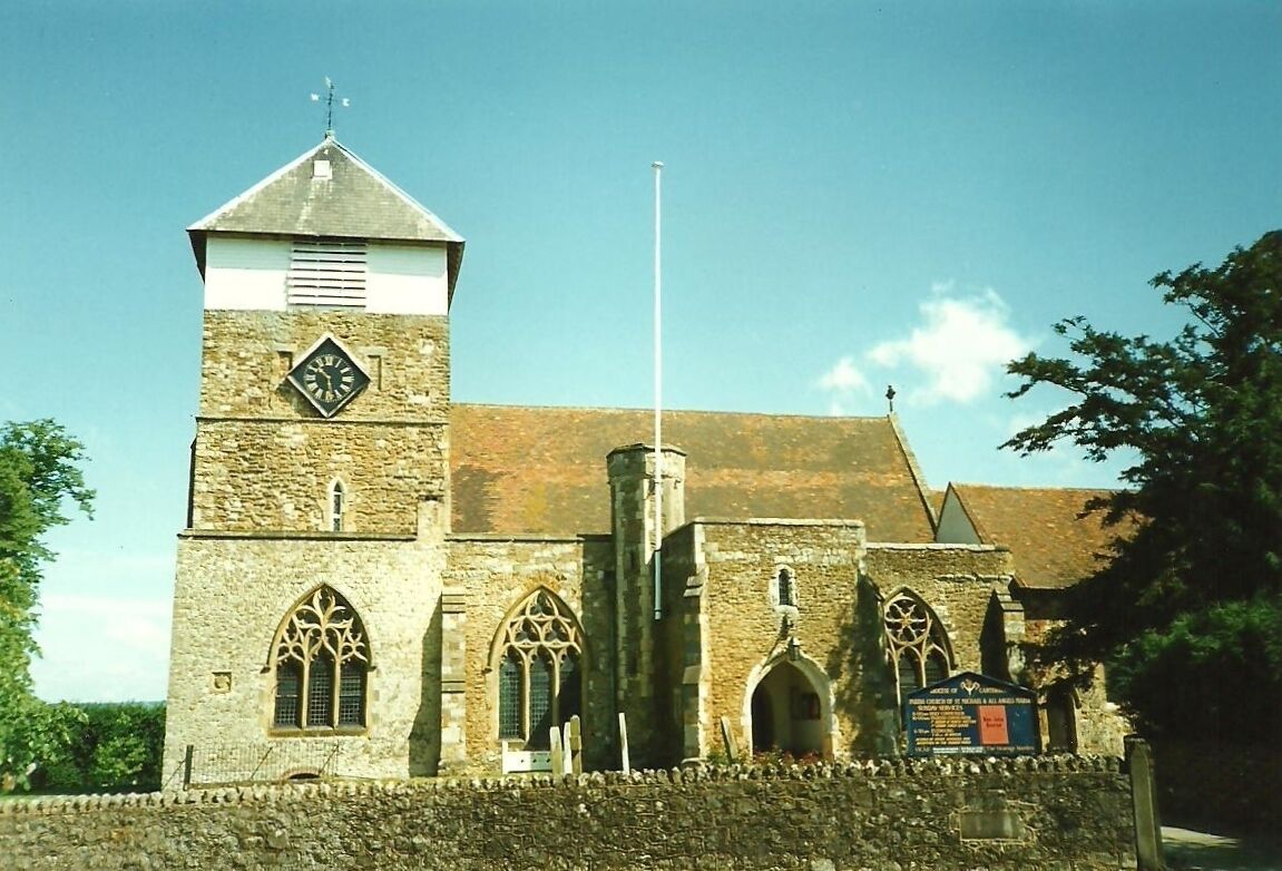 A historic church with a clock tower, arched windows, and a stone wall.