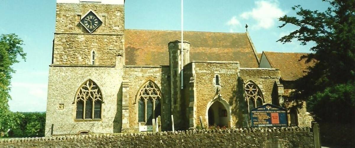A historic church with a clock tower, arched windows, and a stone wall.