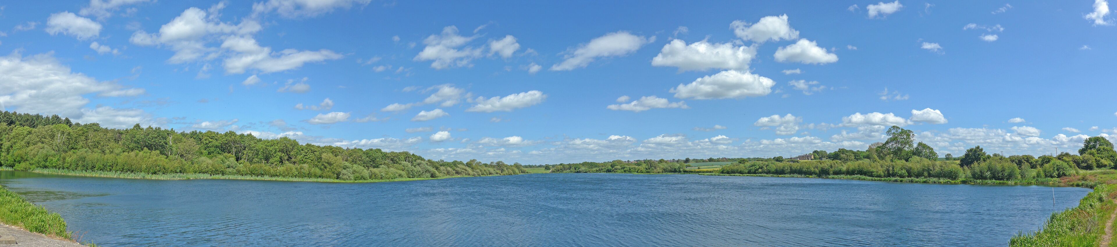 A calm river with a forested bank and a clear blue sky.