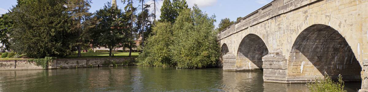 Eine Steinbrücke über einem Fluss, auf dem Schwäne schwimmen.