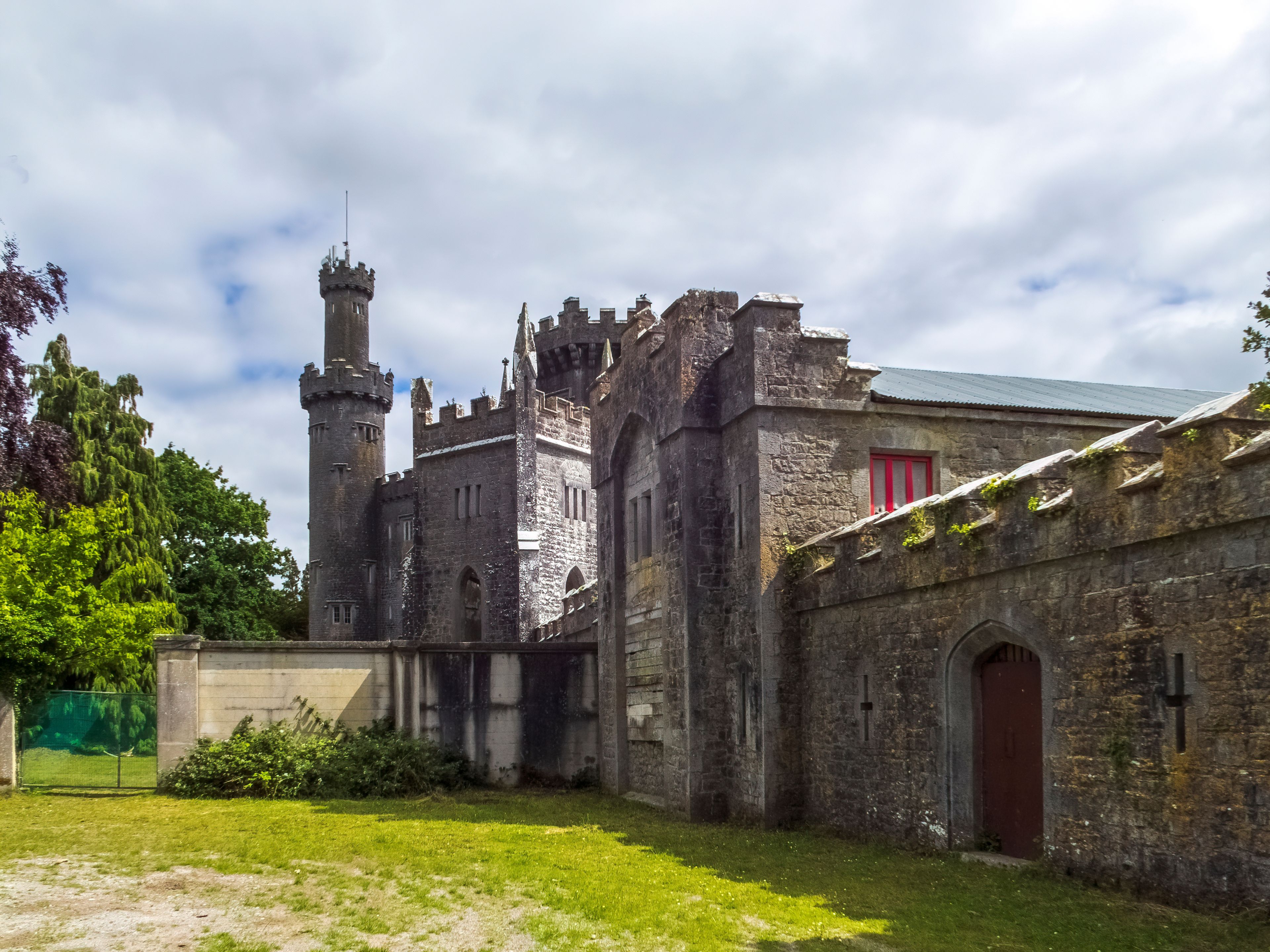 Un château historique doté d’une tour imposante, de murs en pierre et d’une porte rouge.