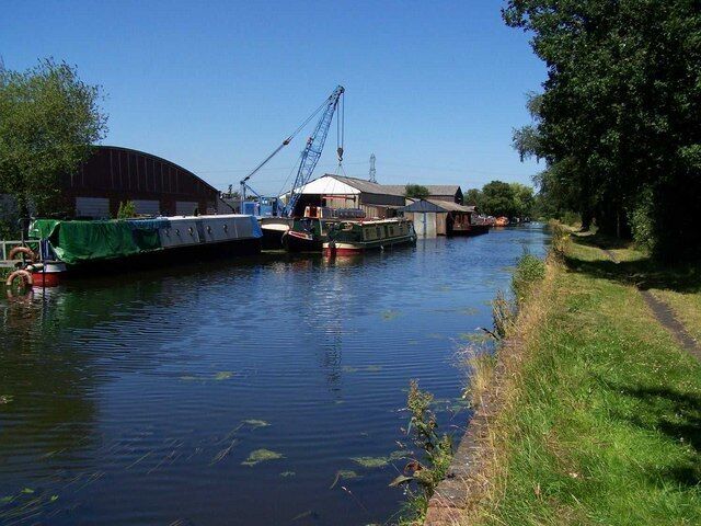 A calm river with boats, a crane, and industrial buildings.