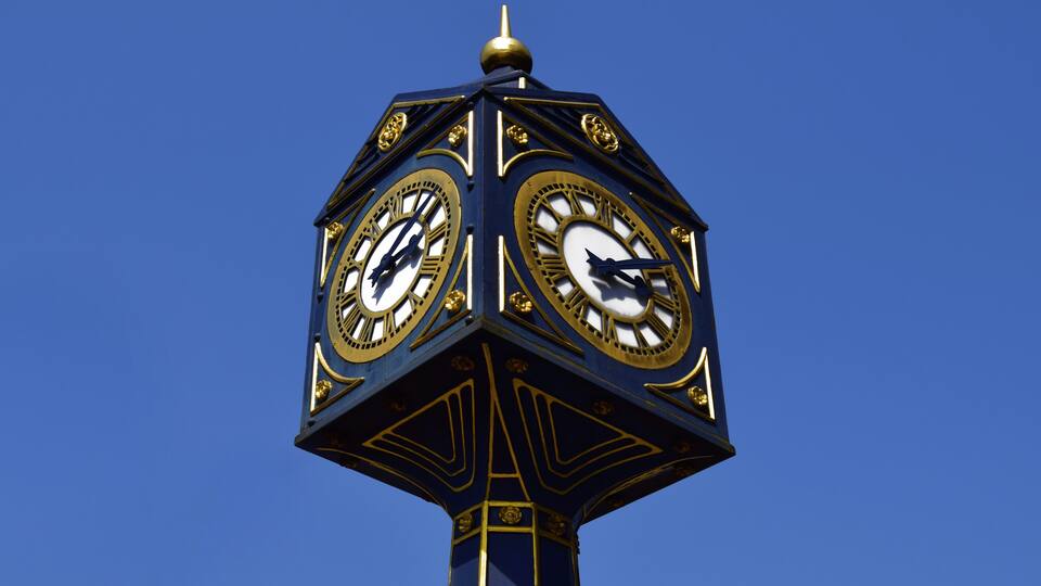 A blue and gold clock tower against a clear blue sky.