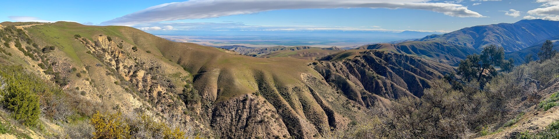 Un paisaje montañoso con colinas ondulantes y vegetación escasa.