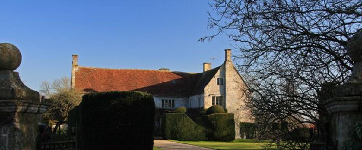 A gravel driveway leading to a stone building with a red roof.