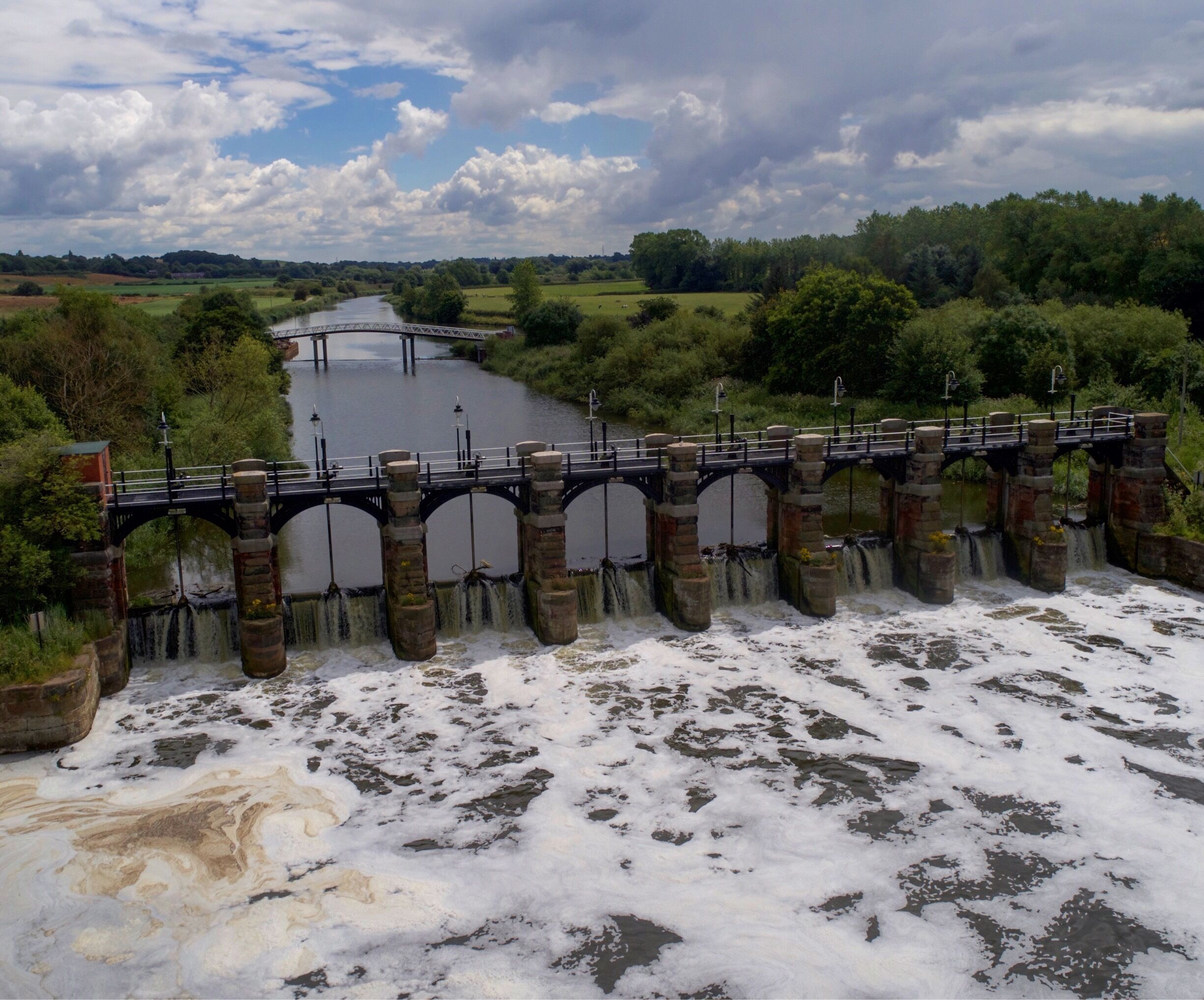 A stone bridge over a river with a dam releasing water.