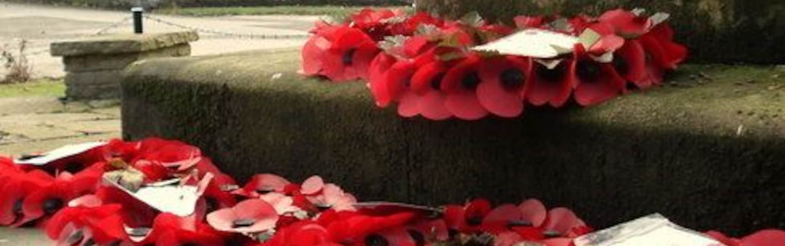 Wreaths on the war memorial at Appleton Thorn, Cheshire, with St Cross parish church in the background