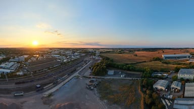 An industrial area with multiple buildings, a railway track, and a sunset in the background.