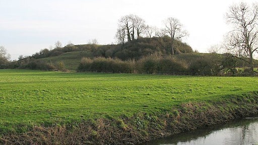 Fenny Castle Motte and Bailey Fenny Castle is a motte and bailey castle set on a small natural hill. The north west end of the hill has been scarped into a steep-sided conical to form a motte, while the south east end has been levelled to create a narrow bailey. Digging in the castle unearthed a wall which defended the summit, as well as iron rings, an iron implement and pottery. In C19 it is recorded that part of the slope at the north west end of the hill was removed to enable easier access around it. In the process the remains of 20 skeletons, possibly of a period predating the construction of the castle, were removed. The river Sheppey can be seen in the foreground.