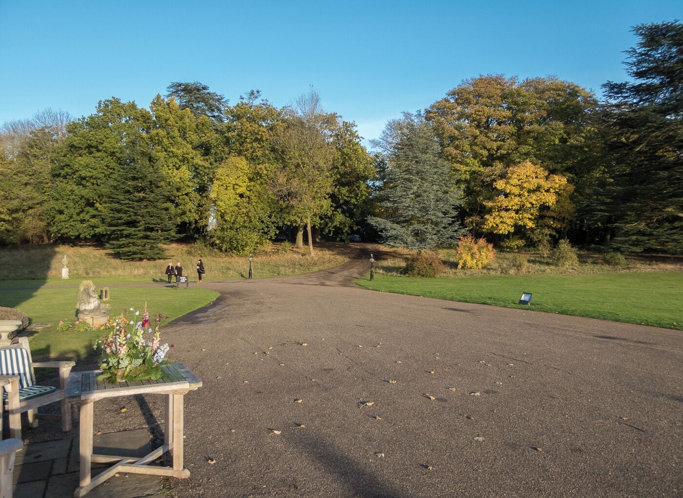 Un sendero de grava en un parque con árboles y una estatua.