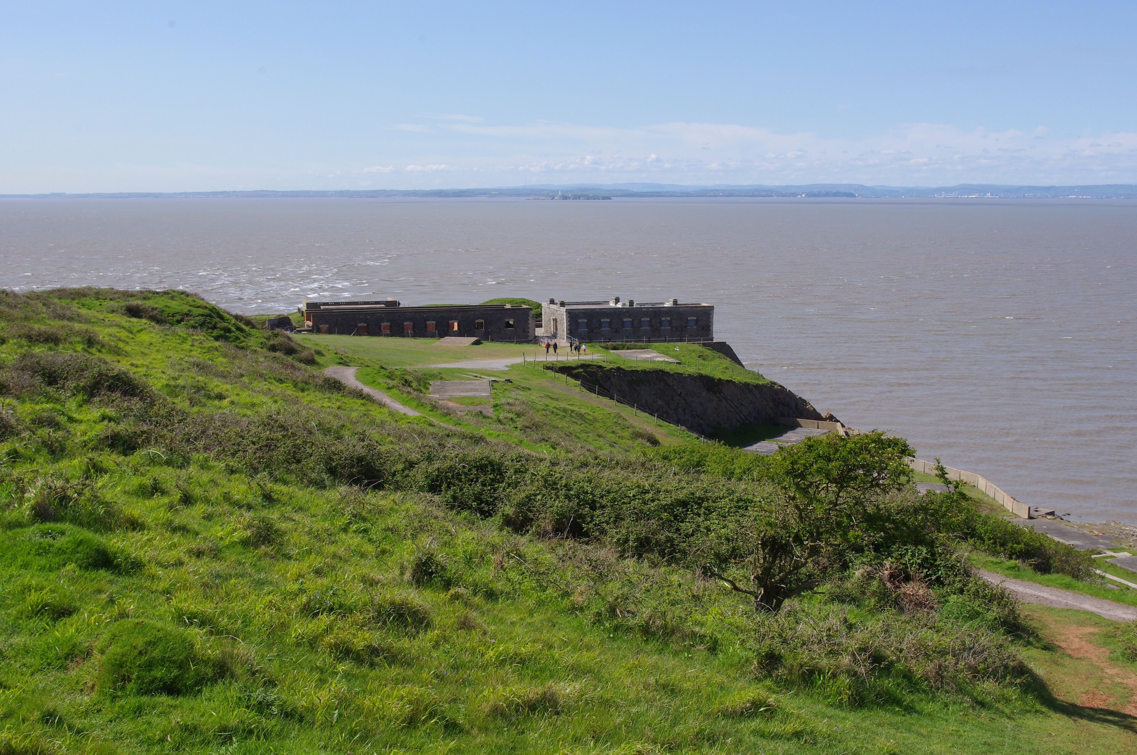 A coastal fortification with a grassy embankment overlooking the sea.
