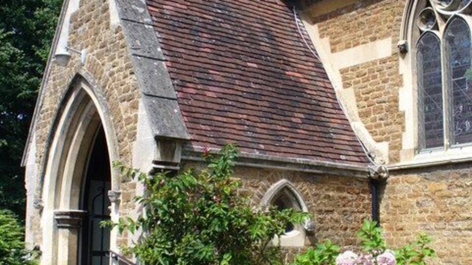 A historic church with a stone facade, a pointed arch entrance, and a rose garden in front.
