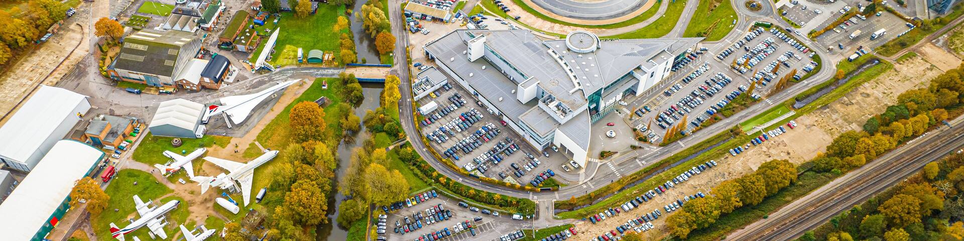 An airport with multiple runways, a parking area, and a river running alongside.