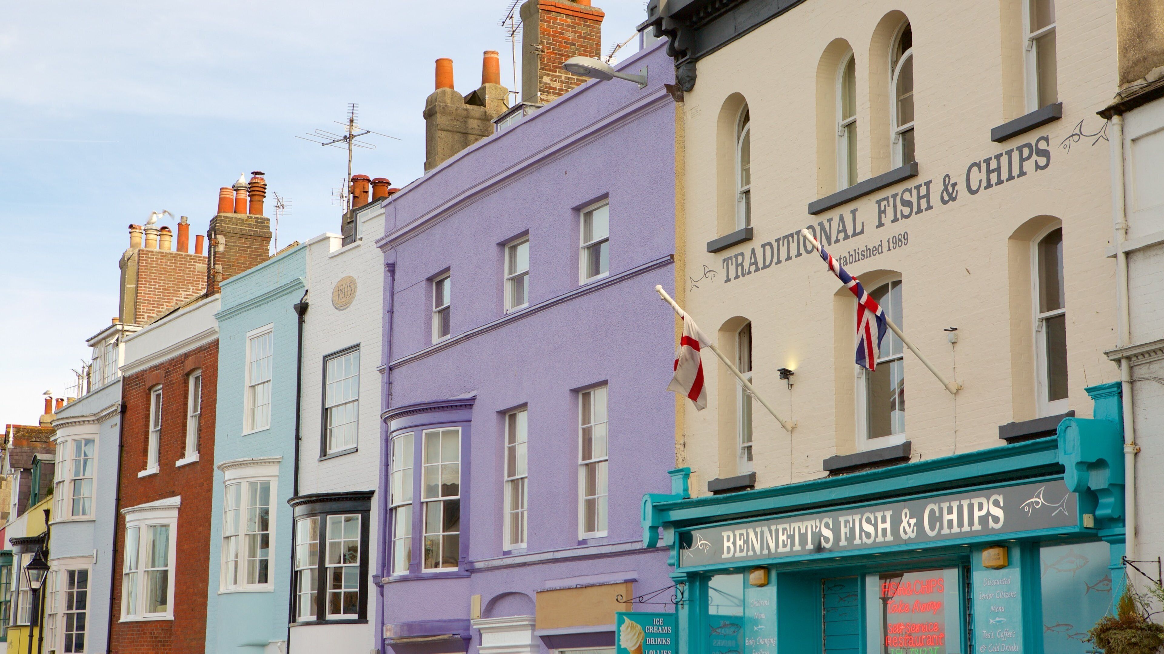 A row of colorful buildings with signs for "Traditional Fish & Chips" and "Bennett's Fish & Chips".