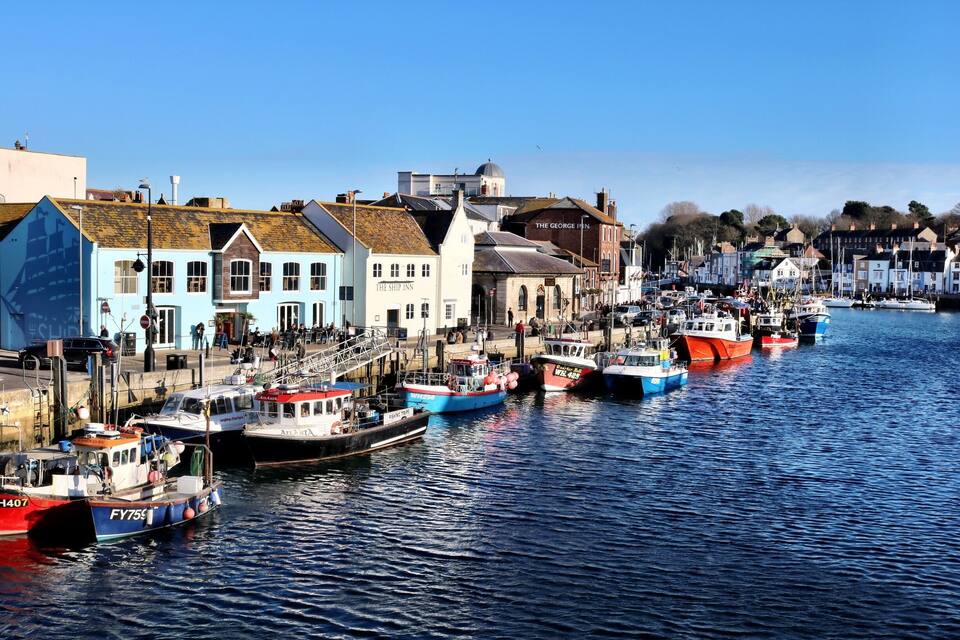 Een haven met kleurrijke boten afgemeerd langs de waterkant, omgeven door historische gebouwen.