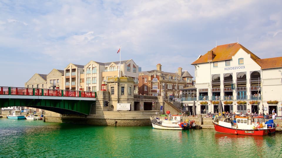 A bridge over a canal with boats docked nearby and buildings in the background.