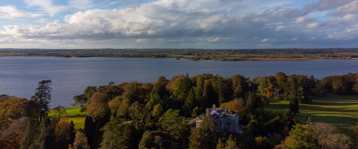 A lake surrounded by trees and a house in the foreground.