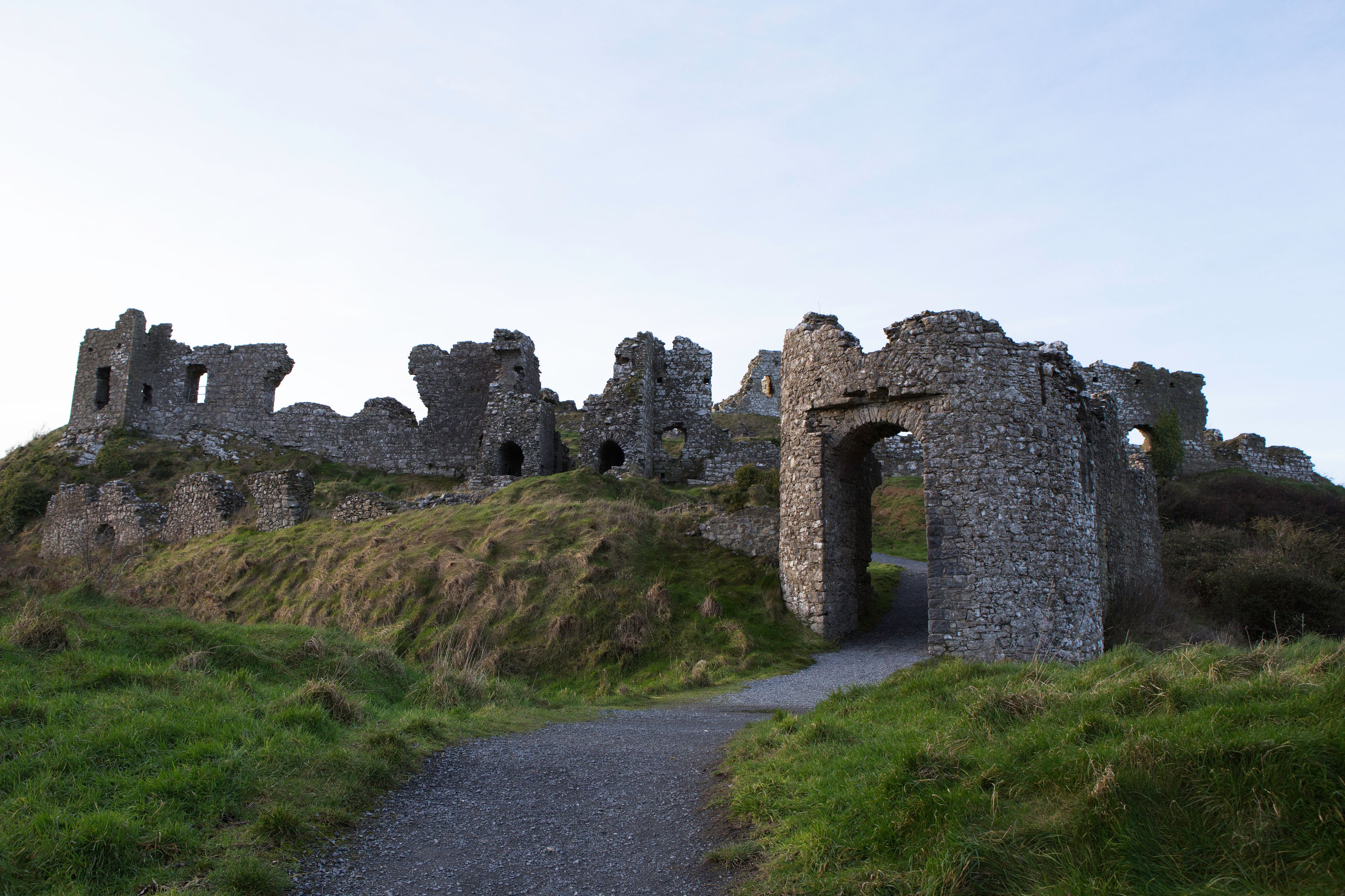 Ruinas de un castillo de piedra histórico con un camino de grava que lo atraviesa.
