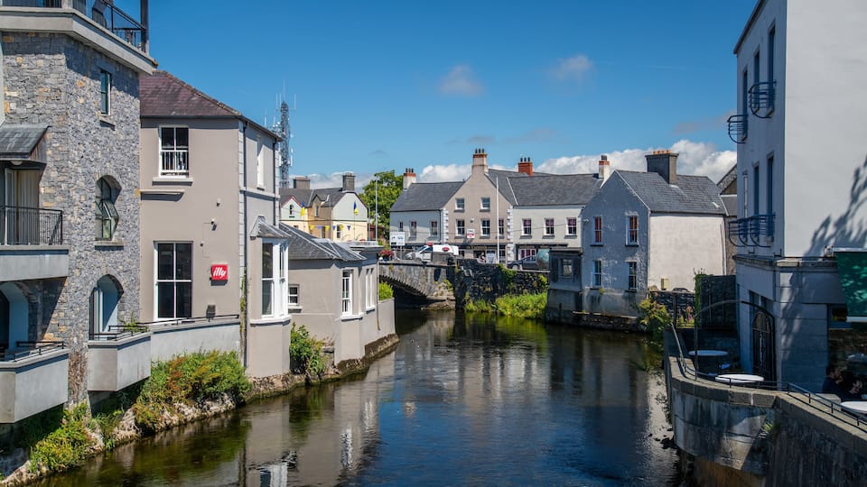A narrow canal flanked by historic stone buildings with a bridge crossing over it.