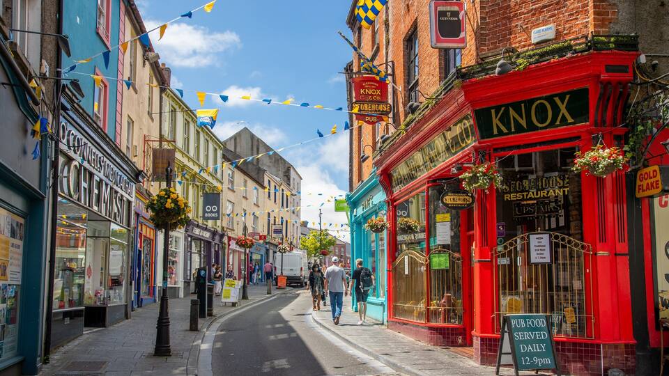 A street lined with colorful buildings, including a red Knox Storehouse Restaurant and a blue Books store.