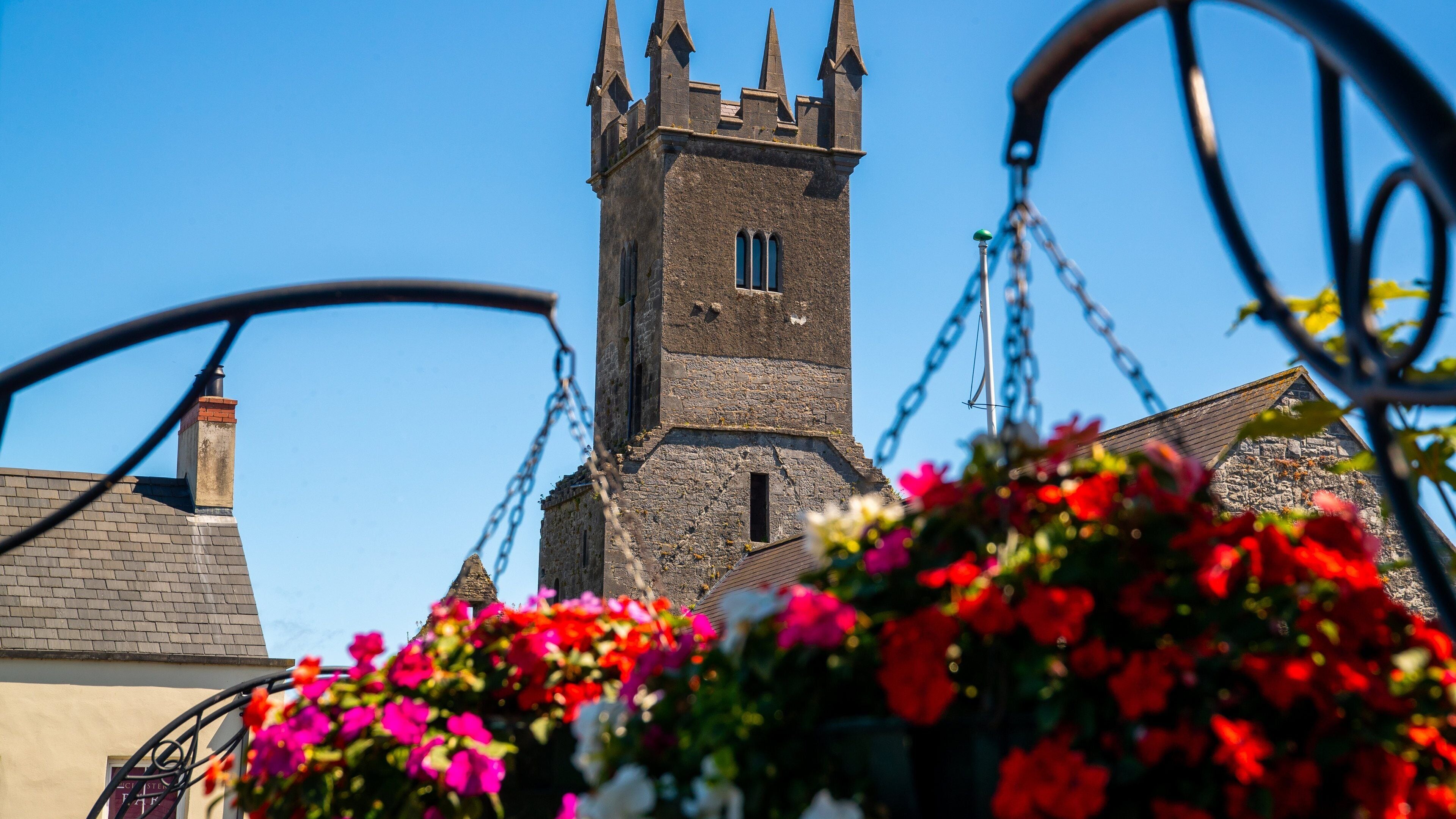 A church tower with a clock and a flower basket in the foreground.