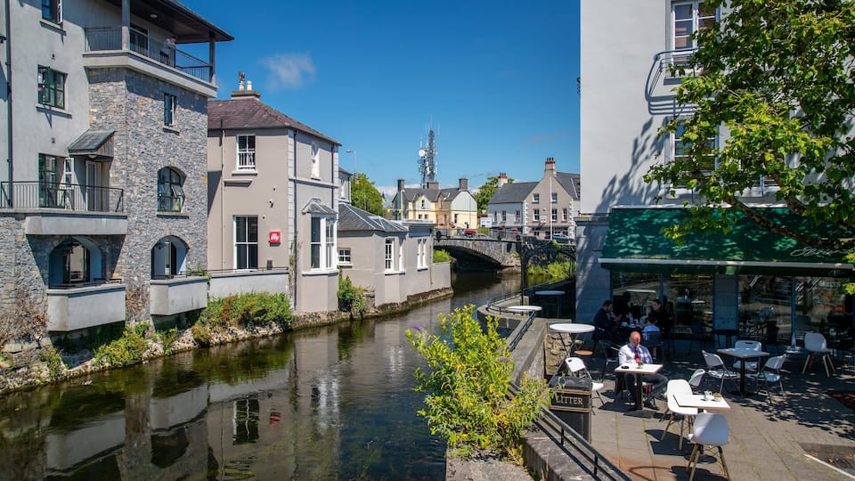 A canal with buildings on one side and a café on the other.