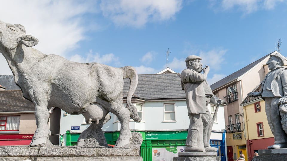 A statue of a cow, a man with a pipe, and a lion statue in an urban setting.