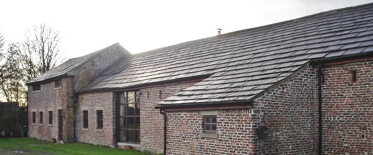 A brick building with a sloped roof and a sign that reads "Swallows Nest Barn".