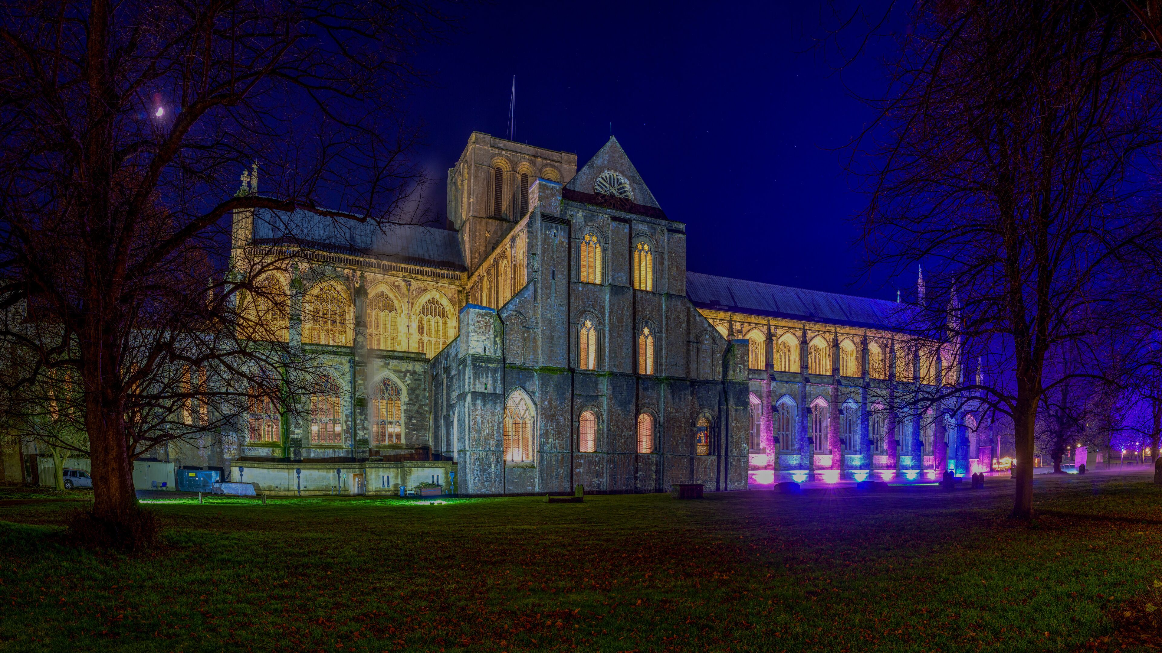 A historic building with Gothic architecture, illuminated windows, and a prominent tower.