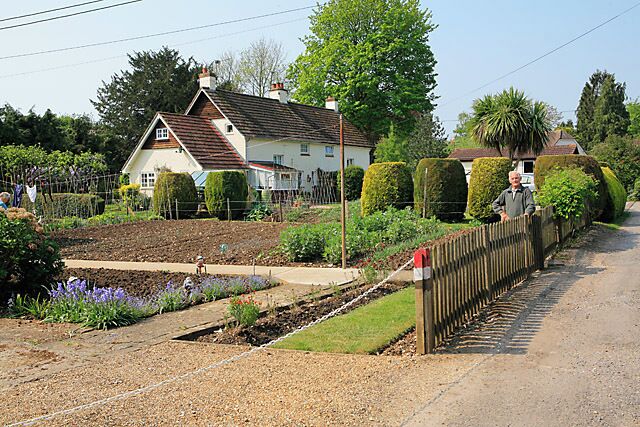 A rural house with a garden, a wooden fence, and a clear sky.